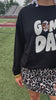 black long-sleeve sweatshirt with white chenille patch lettering reading GAME DAY in uppercase letters and a leopard football as the A in Game Day