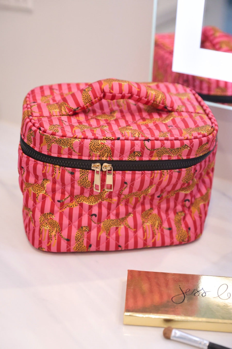 a structured bag with a spacious interior, a secure double zip around closure, a top handle, and gold accents on a quilted body in savannah soirée (pink/raspberry)