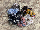 oversized floral scrunchies with lightweight textured fabric, gathered construction, gentle hair-friendly hold, and easy pull-on styling in banana, black, butterscotch, cream, mauve, navy cream, navy teal, sky, and white