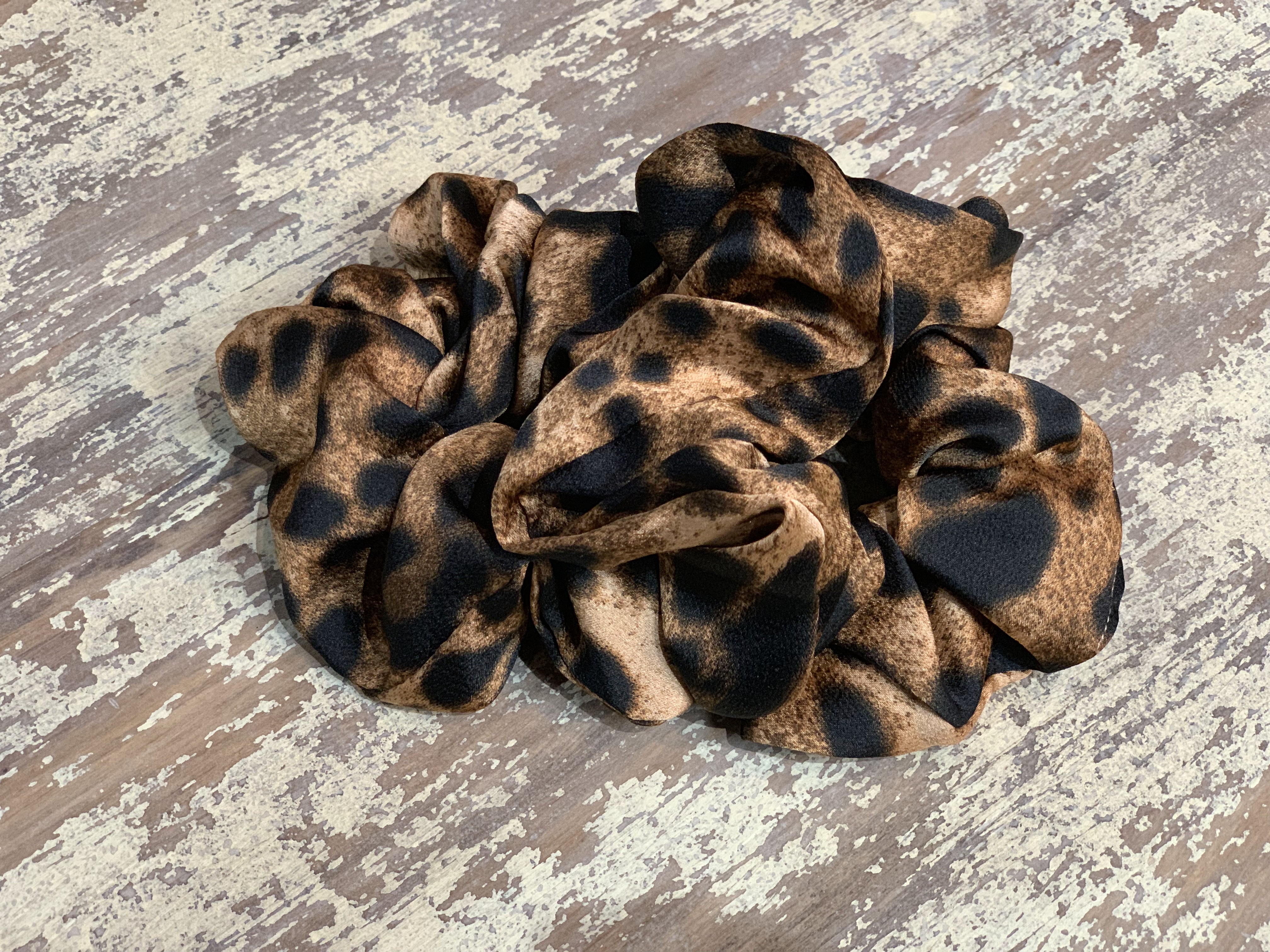 an oversized satin-look leopard scrunchie with glossy animal print fabric, plush gathered construction, lightweight feel, and gentle hair-friendly hold in leopard chocolate
