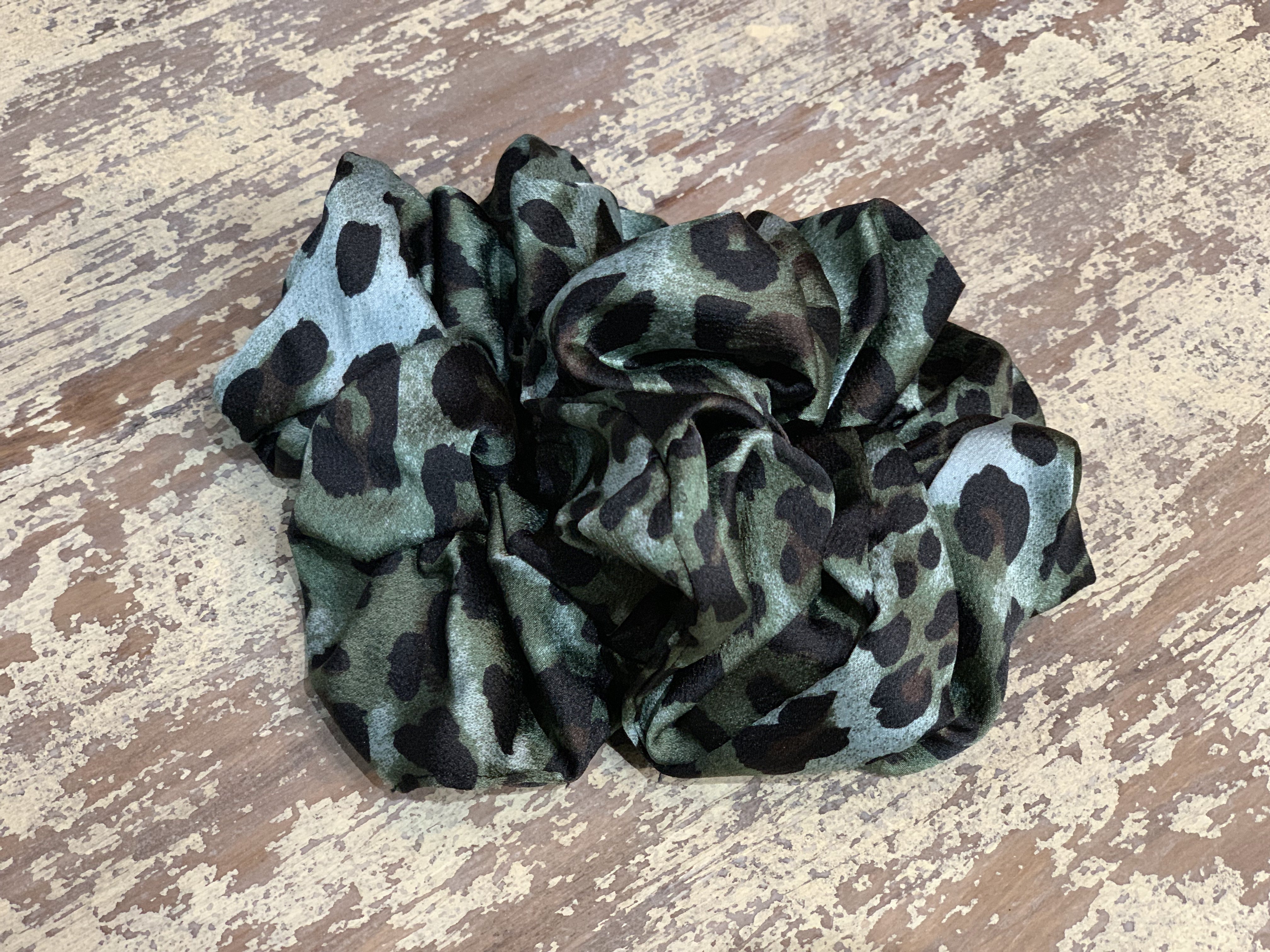 an oversized satin-look leopard scrunchie with glossy animal print fabric, plush gathered construction, lightweight feel, and gentle hair-friendly hold in leopard teal