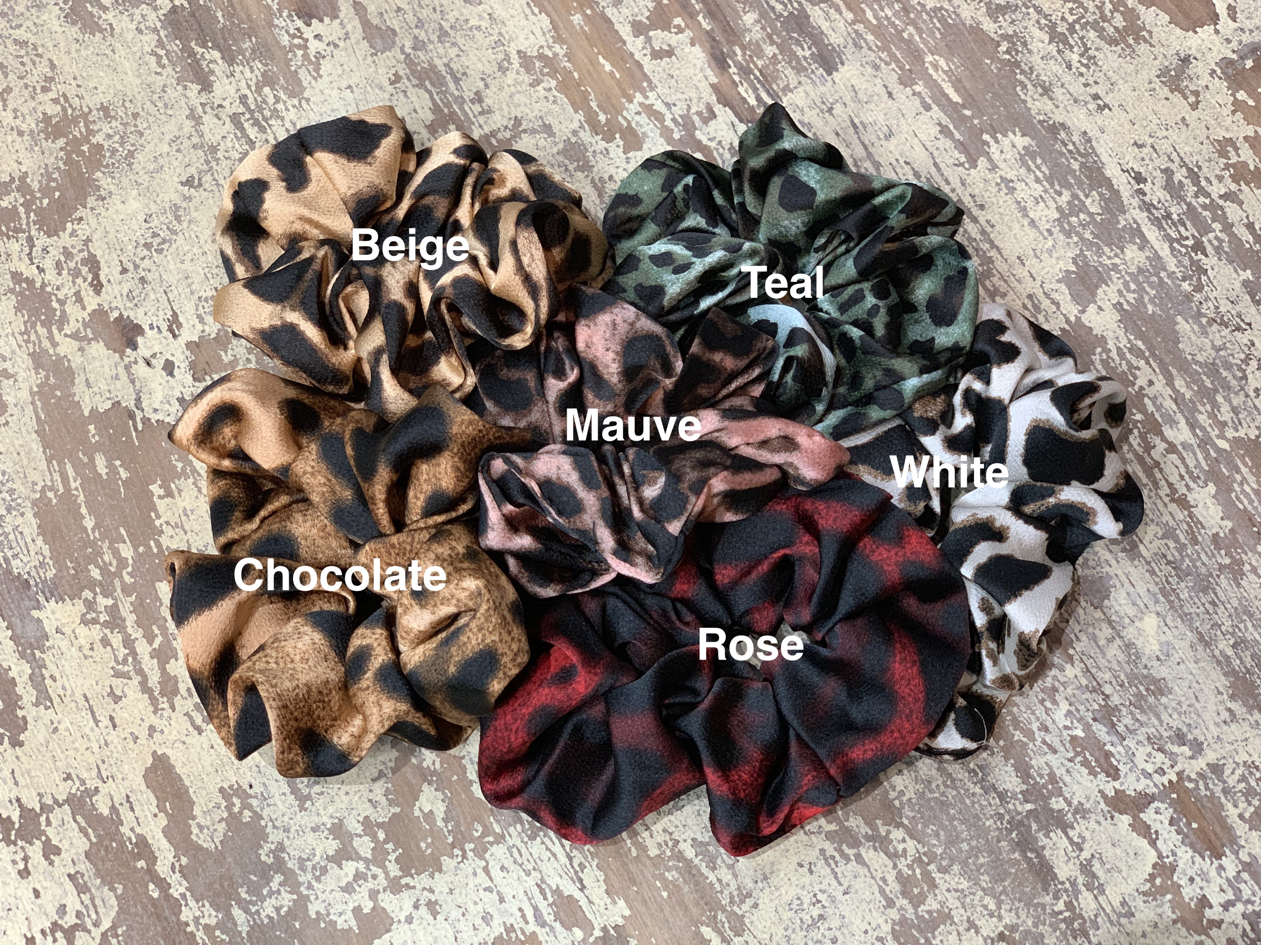 oversized satin-look leopard scrunchies with glossy animal print fabric, plush gathered construction, lightweight feel, and gentle hair-friendly hold in beige, chocolate, mauve, rose, teal, and white