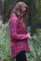 lightweight top with functional buttons, a collared neckline, roll-tab long sleeves, and a high low round hemline on a red plaid pattern