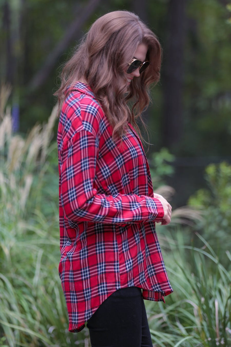 lightweight top with functional buttons, a collared neckline, roll-tab long sleeves, and a high low round hemline on a red plaid pattern