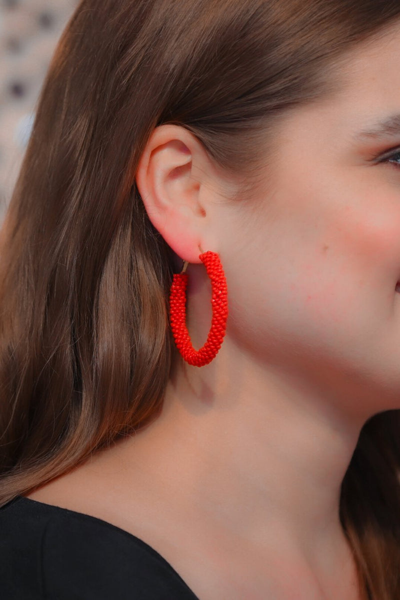 lightweight beaded hoop earrings with a classic circular silhouette in vibrant red