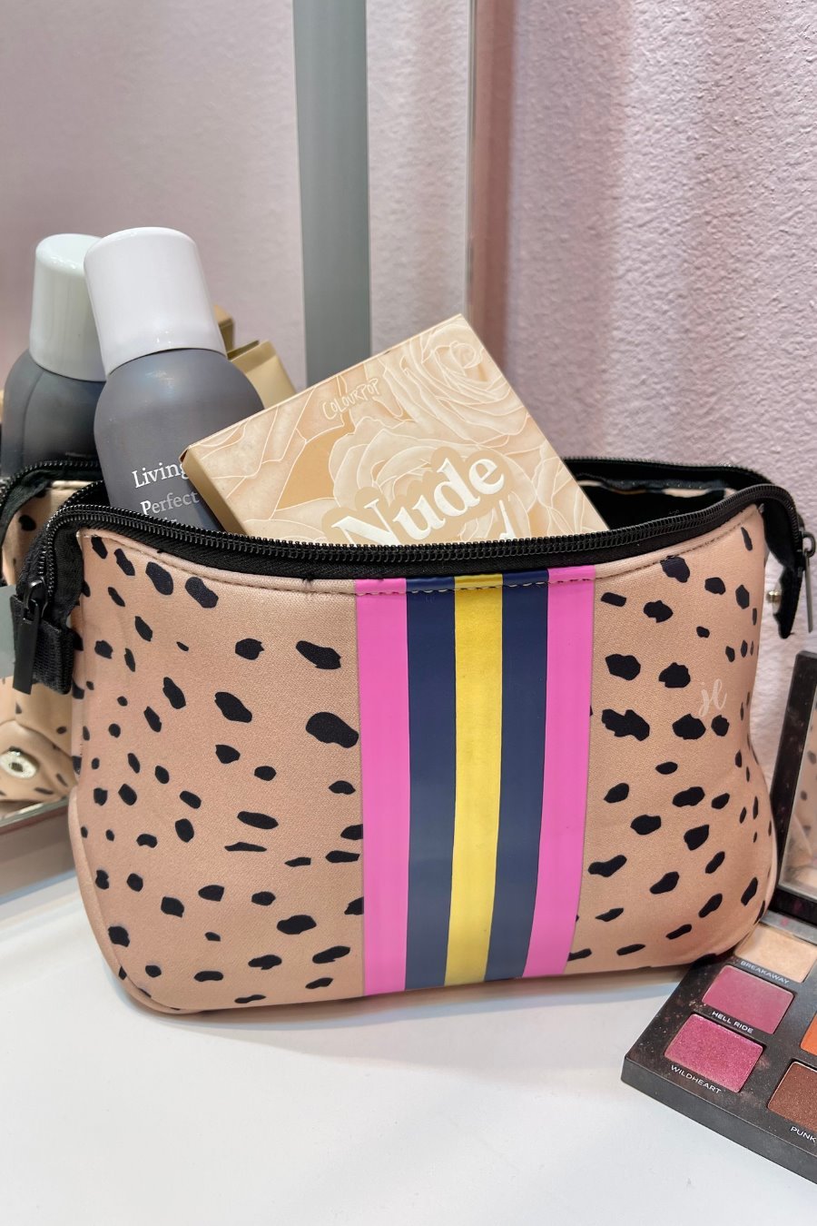 neoprene cosmetic bag in a classic animal print with dual top zippers (black), expandable side snaps (silver), and racing stripes (gold, navy, and pink)