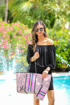 ultra-lightweight tote made of neoprene with a removable hard bottom liner, paracord shoulder straps, removable matching zippered pouch, magnetic side snap closures in silver hardware, black interior (tote and pouch), and racing stripes (navy, pink, and yellow) on a black and pink animal print pattern