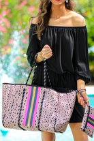 ultra-lightweight tote made of neoprene with a removable hard bottom liner, paracord shoulder straps, removable matching zippered pouch, magnetic side snap closures in silver hardware, black interior (tote and pouch), and racing stripes (navy, pink, and yellow) on a black and pink animal print pattern