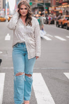 a loose long-sleeve top made of lightweight material covered in shimmering sequins with a collared neckline, fitted button closure cuffs, an accent chest pocket, and a relaxed button-up silhouette that falls into a round high-low hemline in champagne