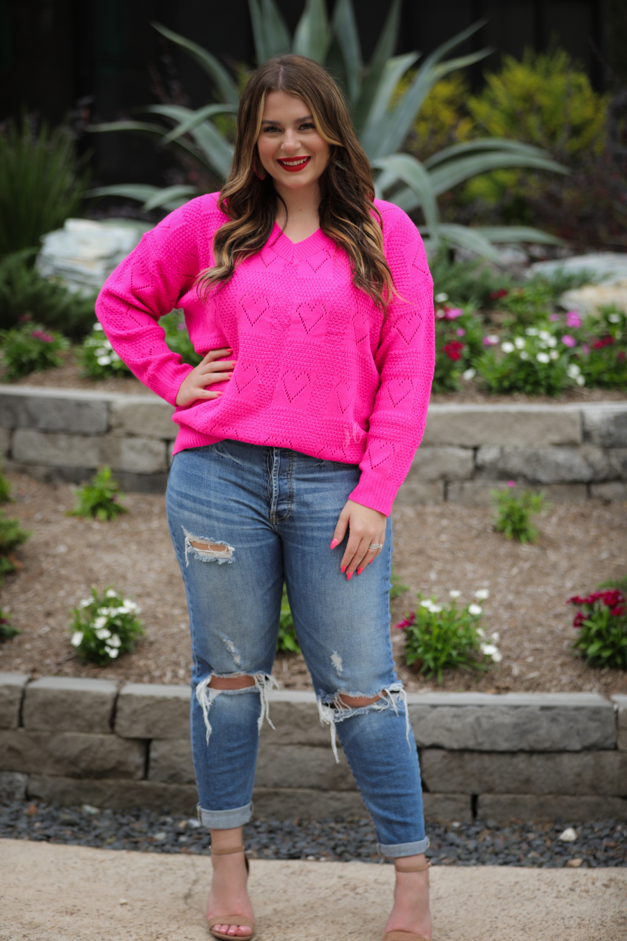 pink long sleeve crew neck sweater with a ribbed hemline and cuffs on a heart cut out pattern print