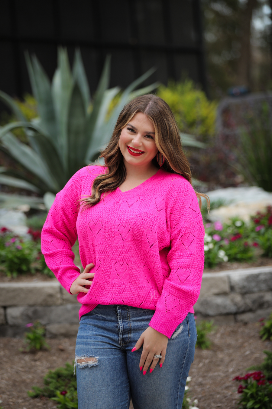 pink long sleeve crew neck sweater with a ribbed hemline and cuffs on a heart cut out pattern print