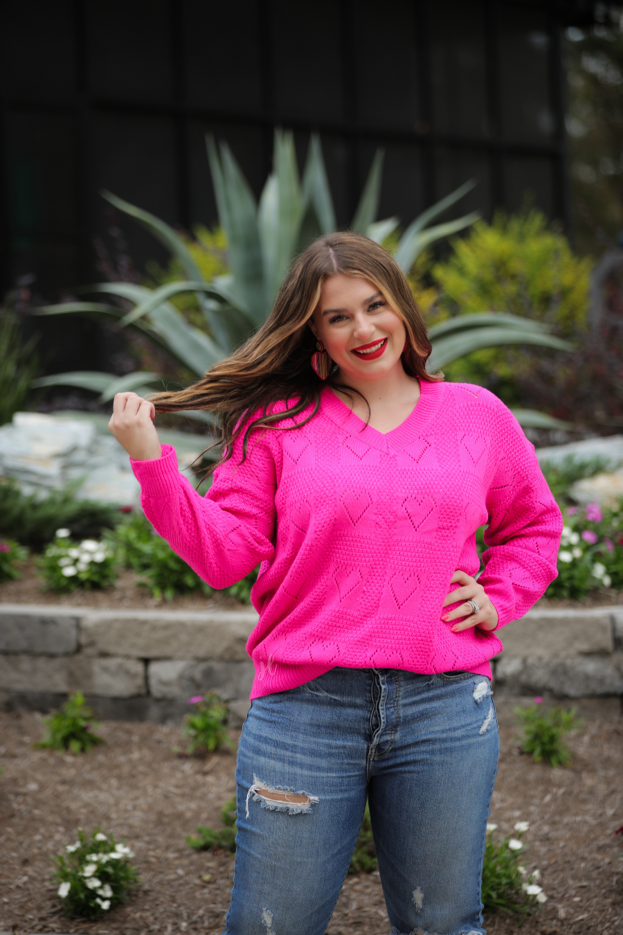 pink long sleeve crew neck sweater with a ribbed hemline and cuffs on a heart cut out pattern print