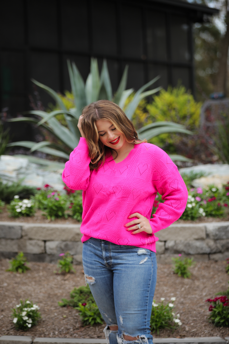 pink long sleeve crew neck sweater with a ribbed hemline and cuffs on a heart cut out pattern print