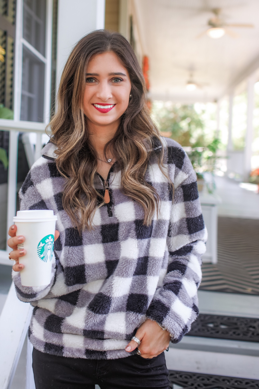 a long-sleeve fluffy pullover with a quarter zip, an adjustable bungee at the hem, and a foldable collar on a classic black and white buffalo plaid pattern fabric