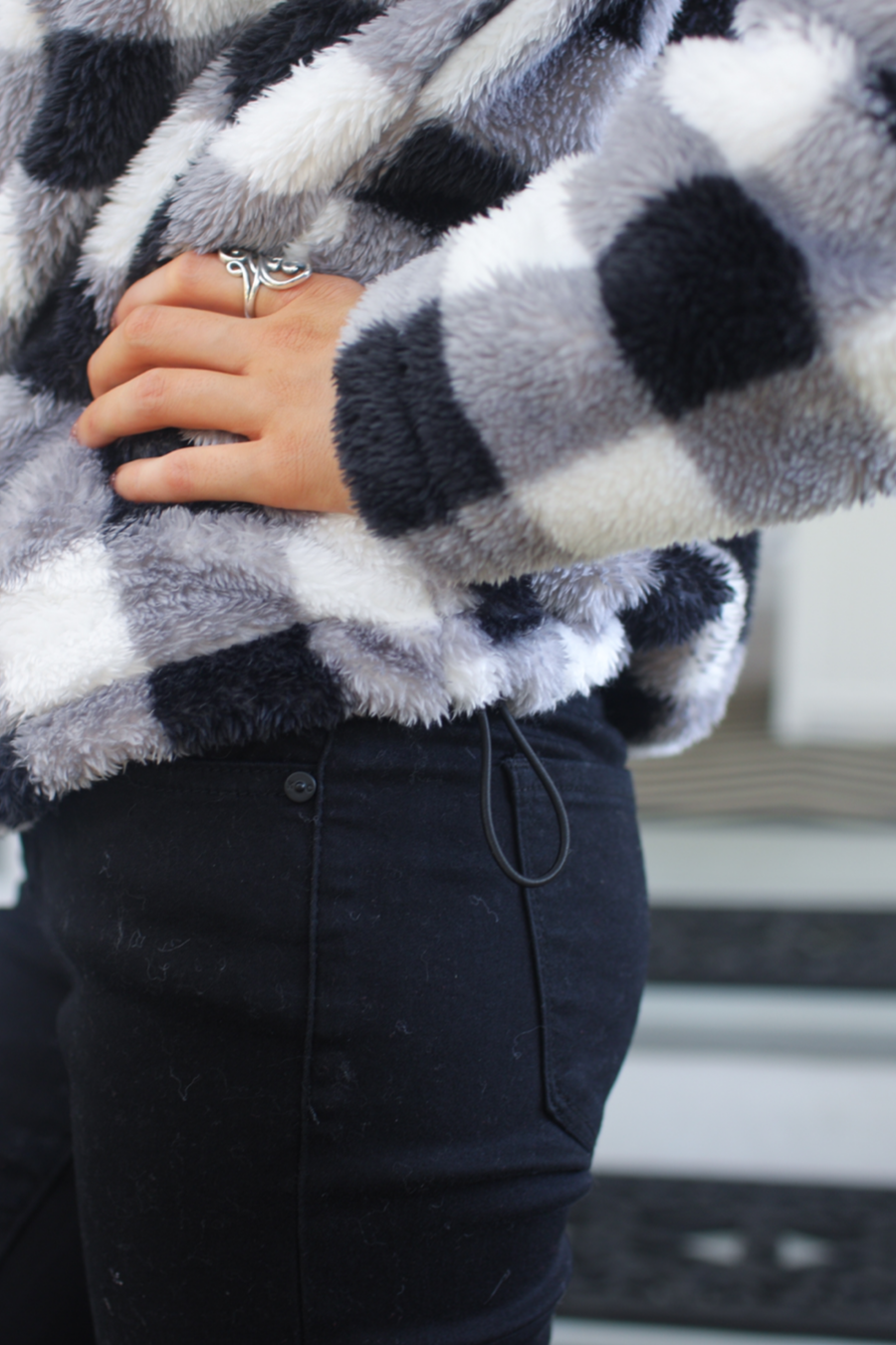 a long-sleeve fluffy pullover with a quarter zip, an adjustable bungee at the hem, and a foldable collar on a classic black and white buffalo plaid pattern fabric