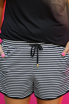 mid-rise, tie waist drawstring with gold bead accent, side pocks, and relaxed fit on a black and white horizontal stripes fabric