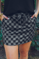 mid-rise relaxed fit everyday skort made of lightweight material with built-in black shorts, drawstring tie, an elastic band on the back, and side pockets, designed on a two-tone black checkered pattern print