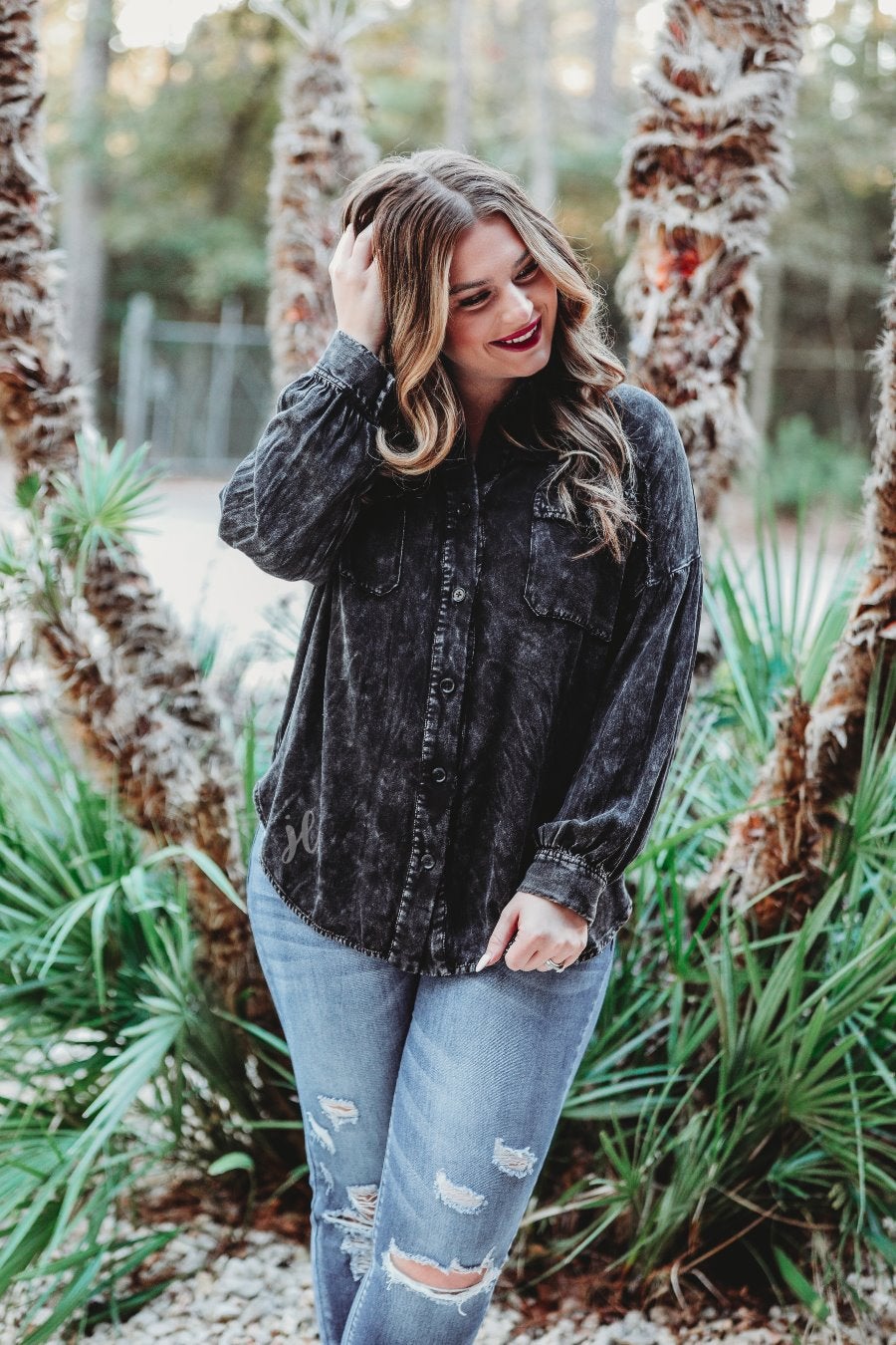 loose long-sleeve top made of soft lightweight material with a button up front, a collared neckline, button closure cuffs, two oversized accent chest pockets, and a slouched silhouette that falls into a rounded hemline with an oversized fit on an acid-washed colored fabric in black