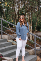 loose long-sleeve top made of soft lightweight material with a button up front, a collared neckline, button closure cuffs, two oversized accent chest pockets, and a slouched silhouette that falls into a rounded hemline with an oversized fit on an acid-washed colored fabric in chambray