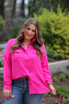 loose long-sleeve top made of soft lightweight material with a button up front, a collared neckline, button closure cuffs, two oversized accent chest pockets, and a slouched silhouette that falls into a rounded hemline with an oversized fit on an acid-washed colored fabric in hot pink