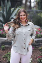 loose long-sleeve top made of soft lightweight material with a button up front, a collared neckline, button closure cuffs, two oversized accent chest pockets, and a slouched silhouette that falls into a rounded hemline with an oversized fit on an acid-washed colored fabric in grey