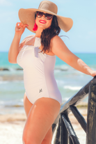 white one-piece swimsuit made of lightweight stretchy material with a one-shoulder neckline, a white matching bow, an adjustable strap, and a padded bust