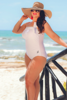 white one-piece swimsuit made of lightweight stretchy material with a one-shoulder neckline, a white matching bow, an adjustable strap, and a padded bust