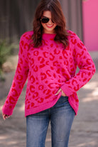 a fuzzy textured long-sleeve sweater with a vibrant pink leopard pattern on a pink base and ribbed detailing on the round neckline, cuffs, and structured hemline