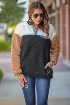 a long-sleeve fluffy pullover with a quarter-leopard snap closure, a faux leopard front chest pocket, a foldable collar, and convenient side pockets on a black, taupe, and white color block fabric that is slightly oversized