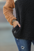 a long-sleeve fluffy pullover with a quarter-leopard snap closure, a faux leopard front chest pocket, a foldable collar, and convenient side pockets on a black, taupe, and white color block fabric that is slightly oversized