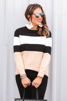 long-sleeve sweater crafted from a soft mid weight knit with bold horizontal blocks of black, tan, and white