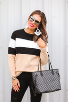 long-sleeve sweater crafted from a soft mid weight knit with bold horizontal blocks of black, tan, and white