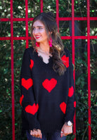 long sleeve sweater made of super soft, stretchy knit fabric with a distressed v-neck and trim on a red heart pattern