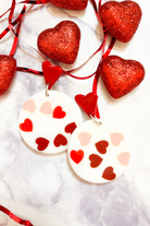 red heart studs accented with dangling acrylic circles and printed hearts in shades of pink and red along with comfort replacement earring backs and plastic disk stopper style in silver