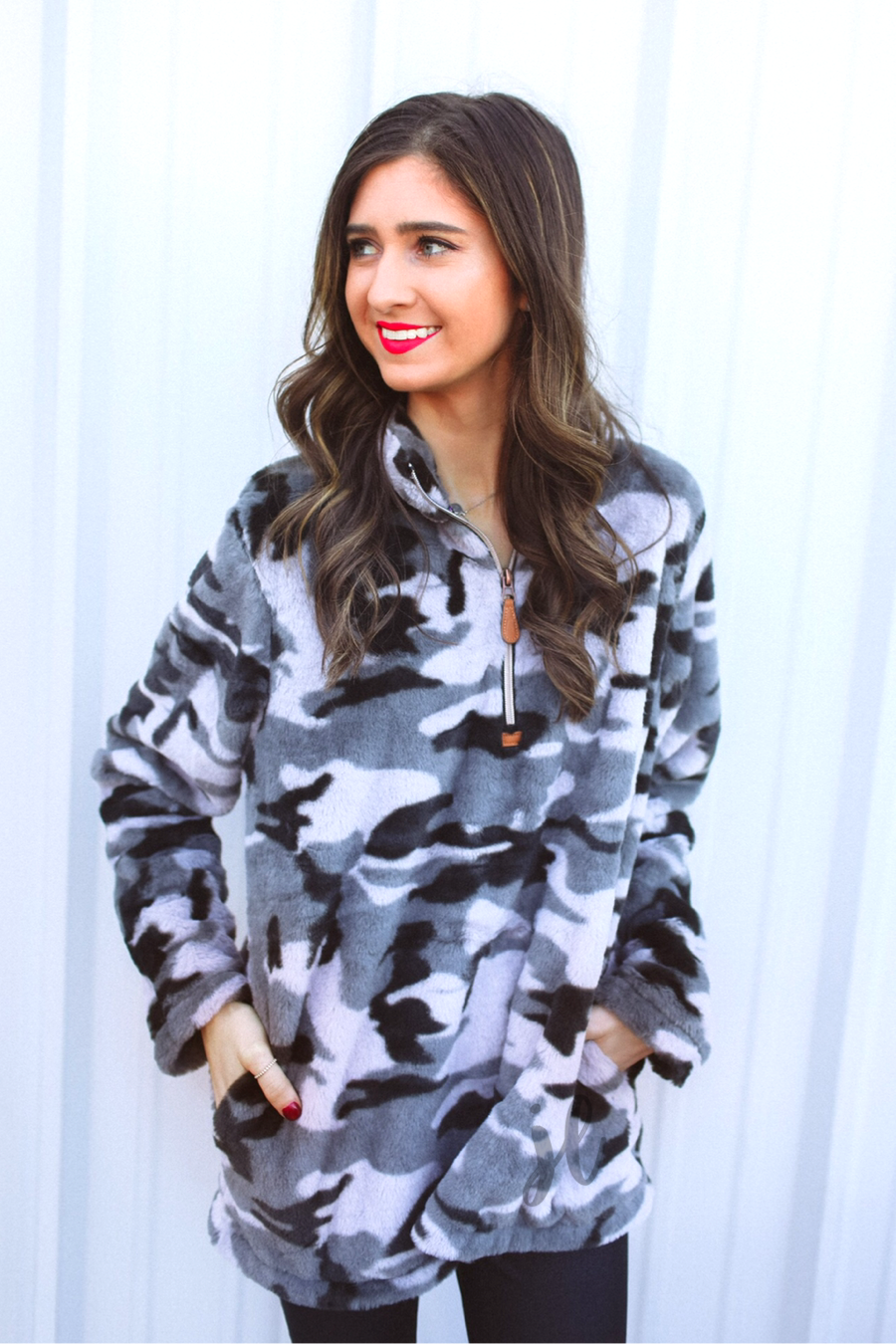 a long-sleeve luxurious faux fur material with a quarter zip, front pockets, and a foldable collar on a camouflage pattern fabric