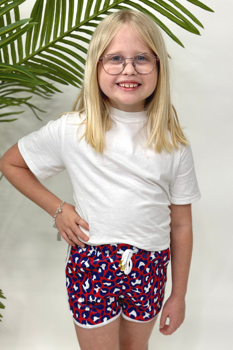 mid-rise relaxed fit activewear shorts with side pockets and a tie waist drawstring with gold bead accents, designed on a vibrant red leopard print and ivory trim