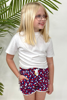 mid-rise relaxed fit activewear shorts with side pockets and a tie waist drawstring with gold bead accents, designed on a vibrant red leopard print and ivory trim