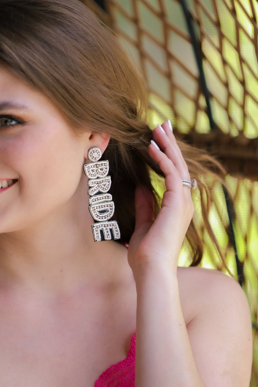 &nbsp;an oversized "BRIDE" written in white beads and small rhinestones, a comfort back earring with a plastic disc stopper in gold, and a black felt back