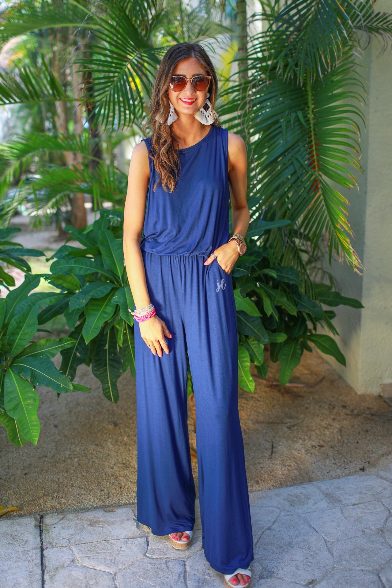 a sleeveless one-piece jumpsuit with 2.5" straps, a keyhole button back, an elastic waist, flare leg, and pockets in navy