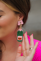 a flower stud adorned with gold, green, orange, and pink beads in the shape of a rosé bottle