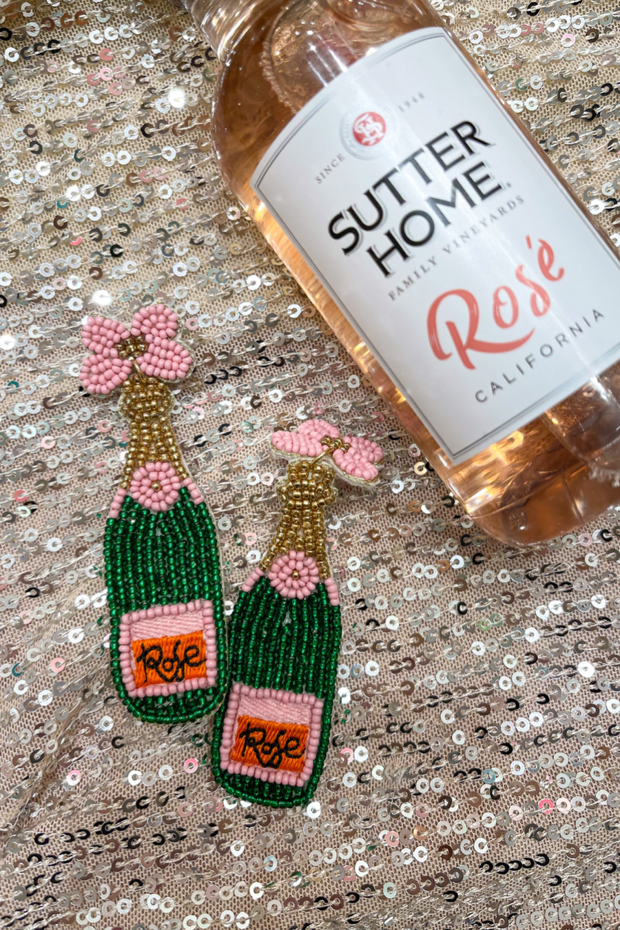 a flower stud adorned with gold, green, orange, and pink beads in the shape of a rosé bottle