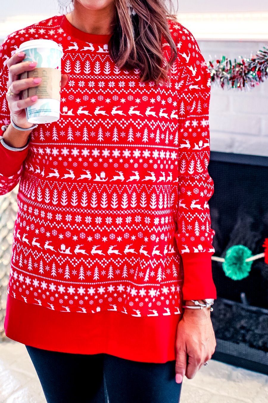 a red long-sleeve tunic made from comfy material with comfy material with a sublimation-printed Christmas pattern print (geometric designs, reindeer, Santa's sleigh, snowflakes, and trees) sublimation detail, ribbed accents (cuffs, neckline, and hem), side slits, and a relaxed fit