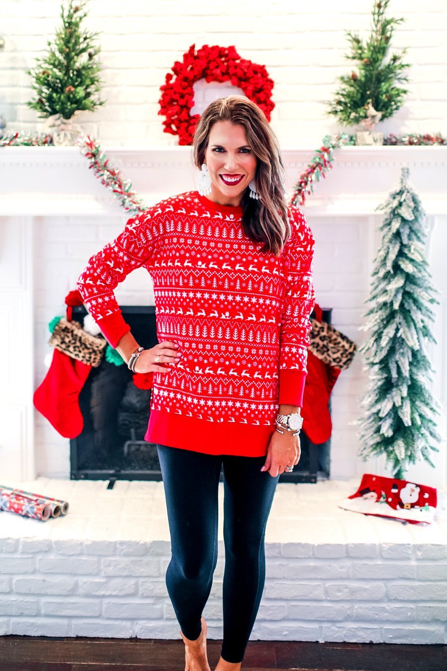 a red long-sleeve tunic made from comfy material with comfy material with a sublimation-printed Christmas pattern print (geometric designs, reindeer, Santa's sleigh, snowflakes, and trees) sublimation detail, ribbed accents (cuffs, neckline, and hem), side slits, and a relaxed fit