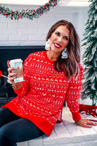 a red long-sleeve tunic made from comfy material with comfy material with a sublimation-printed Christmas pattern print (geometric designs, reindeer, Santa's sleigh, snowflakes, and trees) sublimation detail, ribbed accents (cuffs, neckline, and hem), side slits, and a relaxed fit