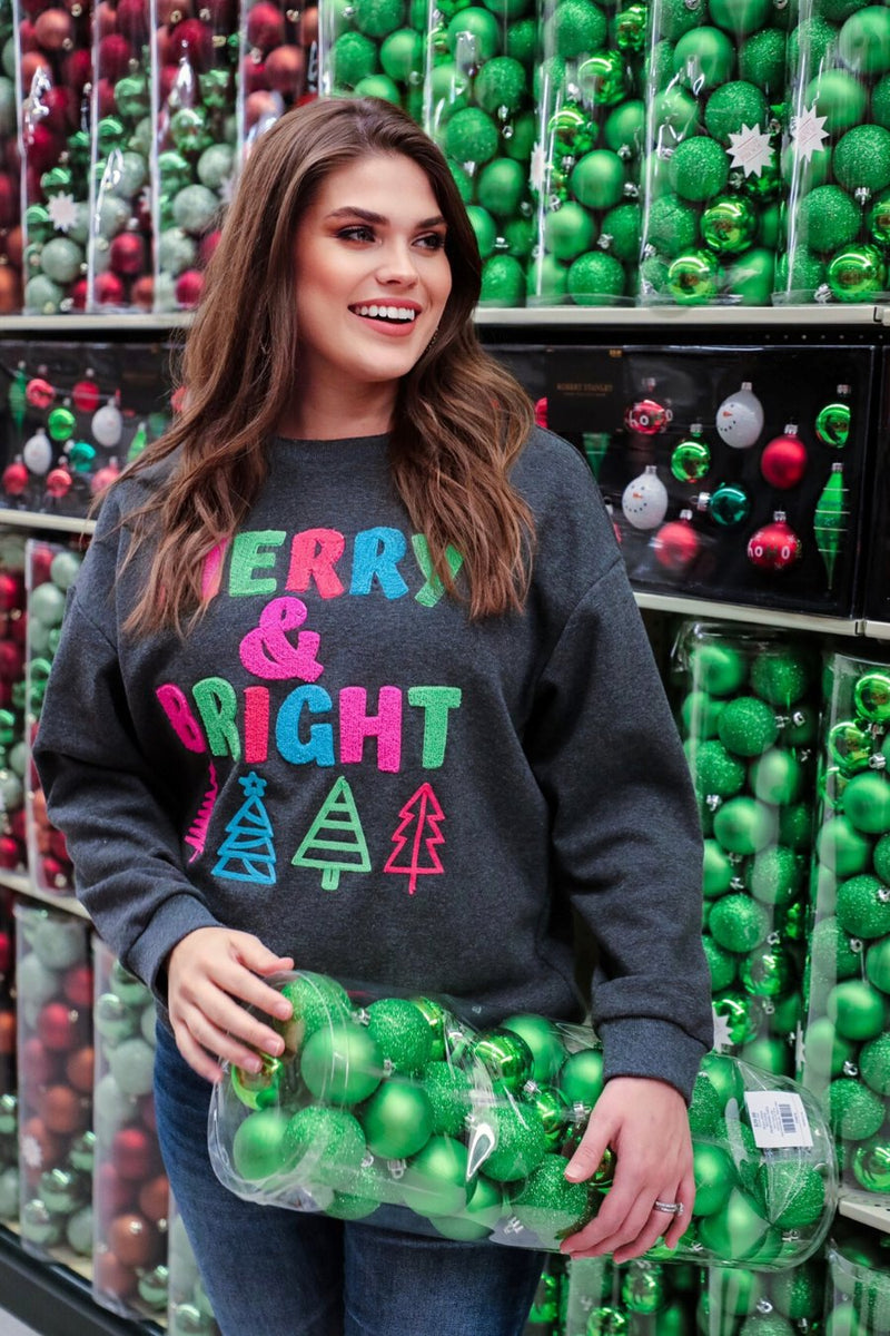 a charcoal long-sleeve sweatshirt with a fuzzy inside, sewn on color chenille letters, and Christmas tree patches