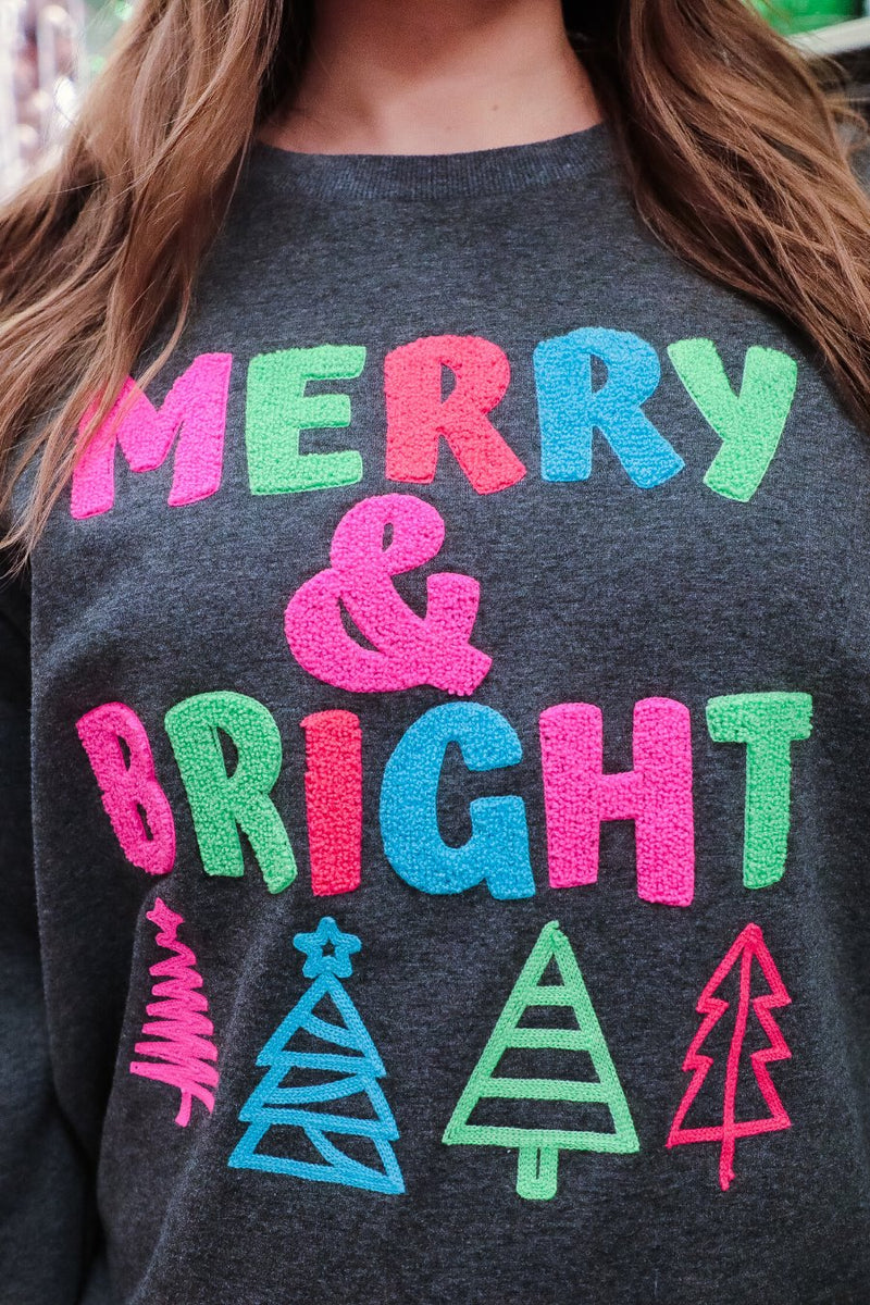 a charcoal long-sleeve sweatshirt with a fuzzy inside, sewn on color chenille letters, and Christmas tree patches