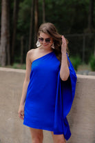 a royal blue one-shoulder mini dress with an asymmetrical neckline and a draping, billowy body creating a relaxed silhouette 