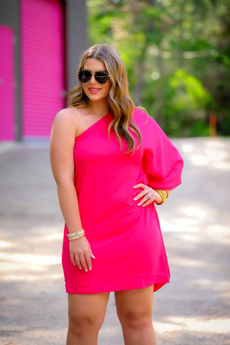 a magenta one-shoulder mini dress with an asymmetrical neckline and a draping, billowy body creating a relaxed silhouette 