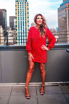 a red long balloon sleeve dress made of sparkly allover sequins, luxe velvet underlay, a keyhole accented upper back with button closure, a round neckline, and subtle elastic cuffs