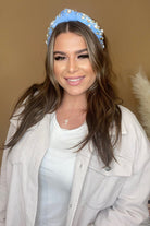 a twisted center knot headband with varying sizes of pearl and rhinestone detailing in blue